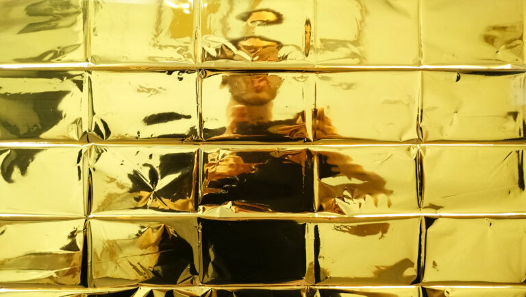 Photo of a person standing behind yellow, glass wall.