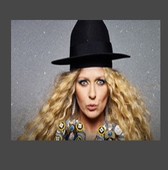 Zdjęcia na któym na tle przypominającym rozgwieżdżone niebo znajduje się Katarzyna Nosowska w czarnym kapeluszu.