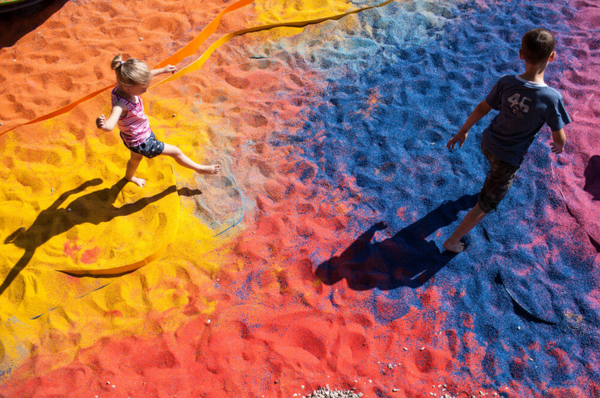 Dzieci chodzące po kolorowym, barwionym kruszywie.