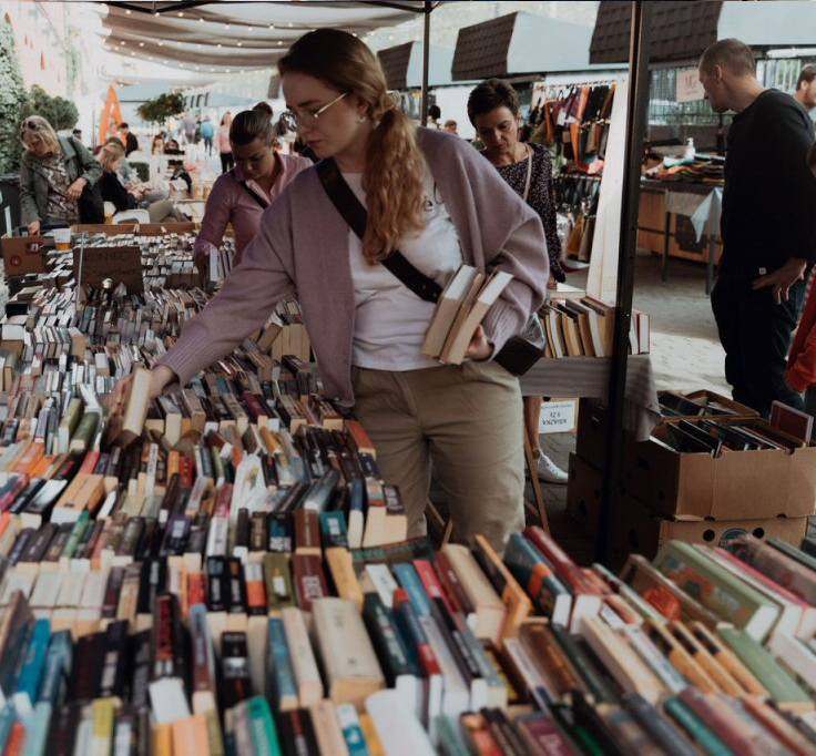 Kobieta przebierająca w książkach wystawionych na bazarze.