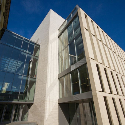 Budynek nowej części Biblioteki Raczyńskich sfotografowany z perspektywy żaby. U góry zdjęcia niebieskie, bezchmurne niebo.