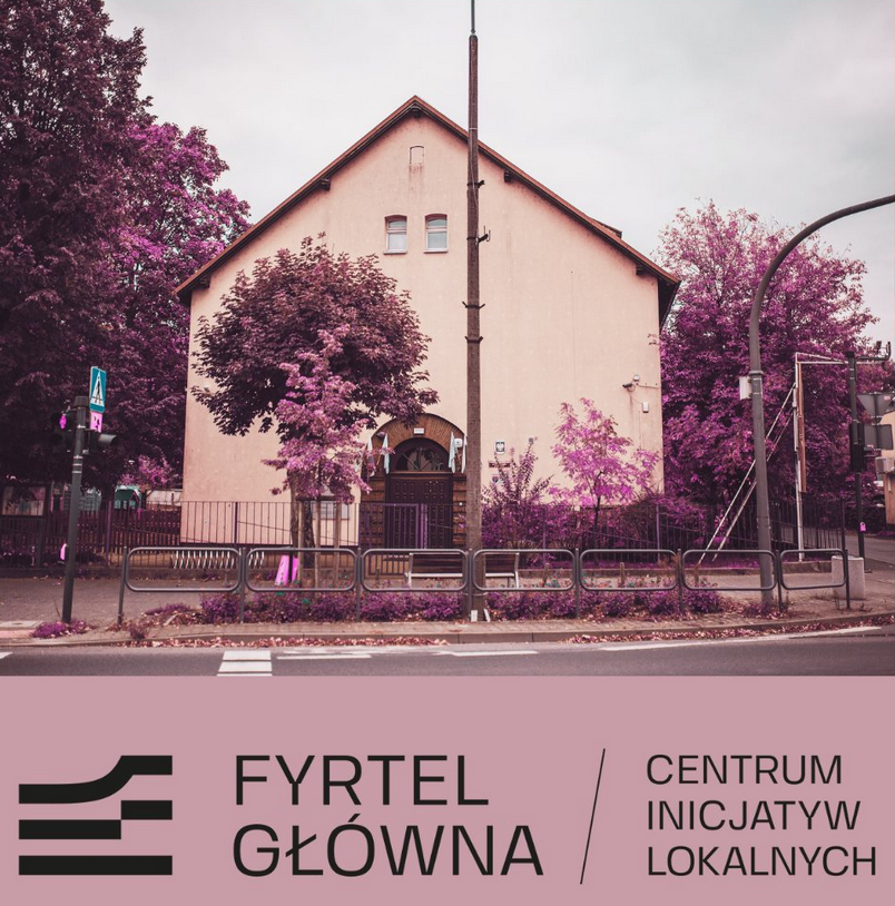 Budynek ze skośnym dachem i stojące przy nim fioletowe drzewa.