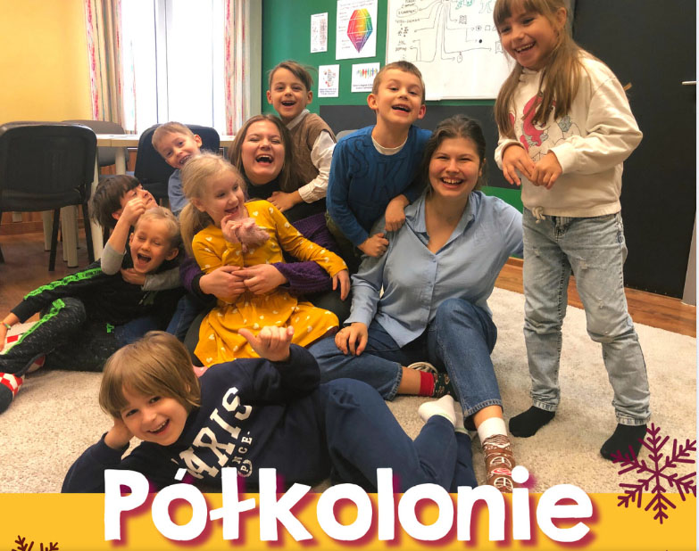 Roześmiane dzieci na dywanie. Wśród nich dwie roześmiane opiekunki "Półkolonie".