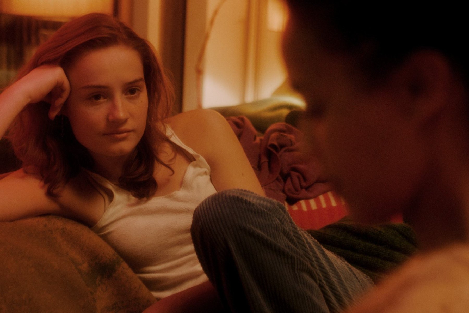 Kobieta siedzi na kanapie, opierając głowę na ręce.