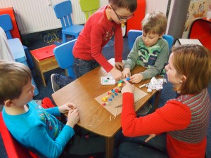 Dzieci przy stole podczas zajęć z plasteliną.