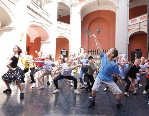 Wychowankowie szkoły baletowej tańczą na dziedzińcu szkoły.