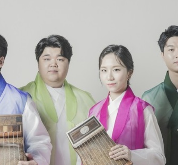 Kolorowa fotografia ukazuje cztery osoby pochodzenia koreańskiego, stojące na wprost aparatu. Trzech mężczyzn oraz kobieta ubrani są w tradycyjne koreańskie stroje. Dwoje muzyków trzyma w dłoniach instrumenty którymi są cytry. Składają się z płaskiego pudła oraz strun.