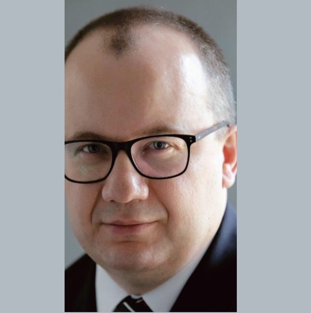 Grafika to zdjęcie portretowe Adama Bodnara w garniturze. Były Rzecznik Prawo Obywatelskich patrzy pewnie w obiektyw.