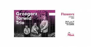 Grafika przedstawia czarno-białe zdjęcie trzech mężczyzn. Jeden z mężczyzn trzyma talerz od perkusji. Na górze pada na nich fioletowe światło.