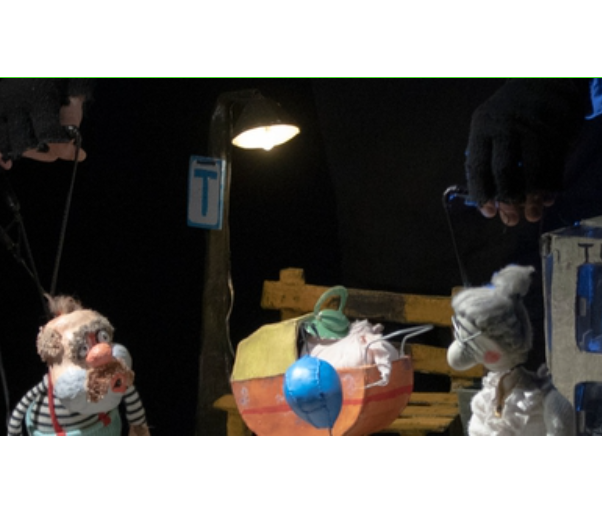 na zdjęciu dwie lalki teatralne: starszy pan stoi po lewej stronie, starsza pani po prawej, pomiędzy nimi wózek dziecięcy. Nad lalkami widoczne ręce aktorów.