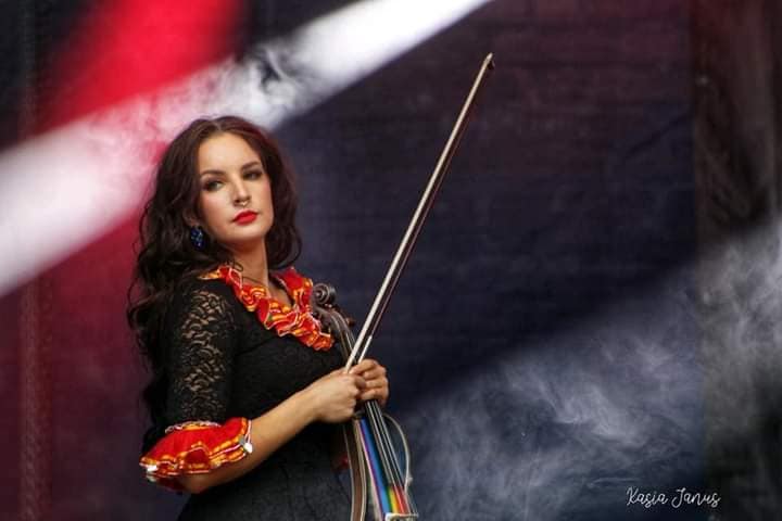 Kobieta z instrumentem stojąca na scenie.