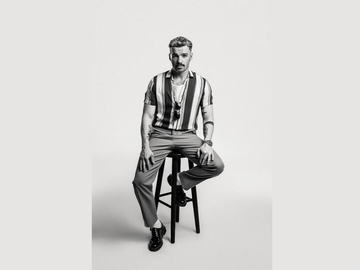 Mężczyzna siedzi na krześle na czarno-białym zdjęciu.