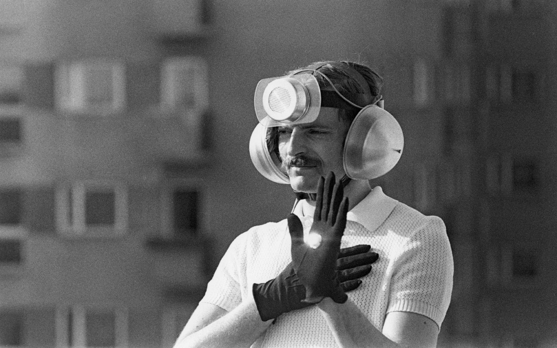 Mężczyzna w rękawiczkach, słuchawkach i głośnikiem na czole.