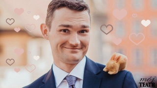 Zdjęcie przedstawia uśmiechniętego mężczyznę w marynarce i koszuli z krawatem, mającego na lewym ramieniu maskotkę wiewiórki.