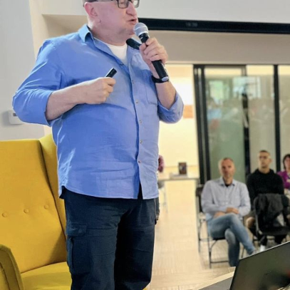 Mężczyzna w kaszkiecie mówi do mikrofonu na spotkaniu autorskim.