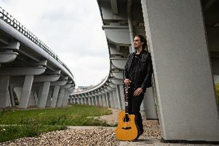 Michał Obrębski z gitarą pod wiaduktem.