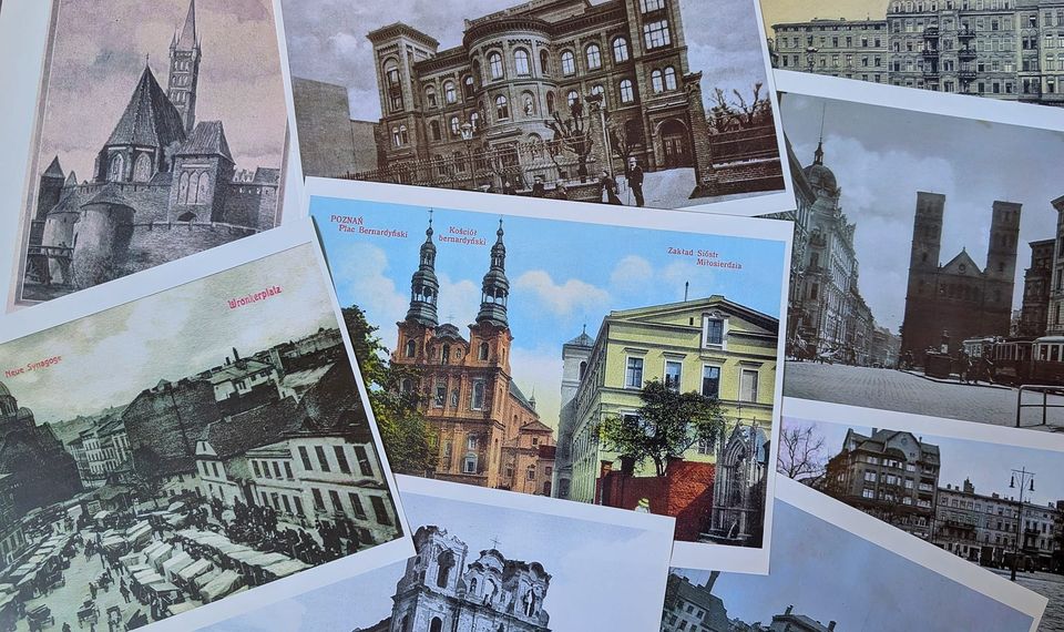 Zdjęcie przedstawia kolekcję pocztówek poukładanych na powierzchni. Te pocztówki prezentują różne sceny architektoniczne, w tym stare budynki, kościoły i panoramy miasta. Pocztówki różnią się tonacją kolorystyczną, niektóre są w sepii, sugerując starszy charakter, podczas gdy inne są kolorowe, co może wskazywać na bardziej niedawne wydanie. Obrazy na pocztówkach mają historyczne i kulturowe znaczenie, stanowiąc migawkę dziedzictwa architektonicznego z różnych okresów.
