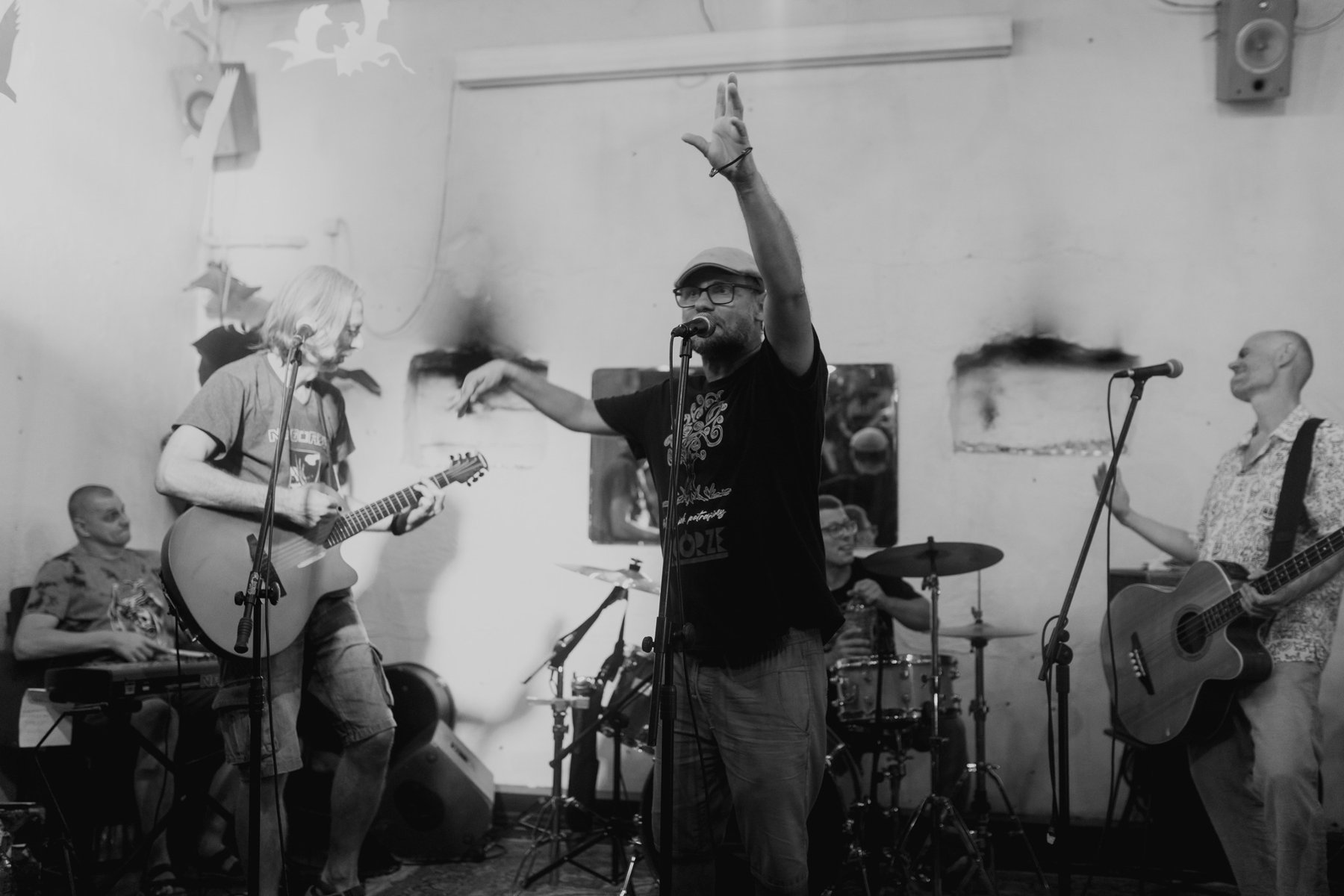 Czarnobiałe zdjęcie zespołu muzycznego składającego się z pięciu mężczyzn. Jeden śpiewa, dwóch gra na gitarach. Z tyłu jeden mężczyzna gra na perkusji a drugi na pianinie elektrycznym.