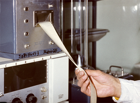 Z maszyny wychodzi taśma paieru z wydrukie. Taśmę trzyma dłoń najprawdopodobniej lekarza.