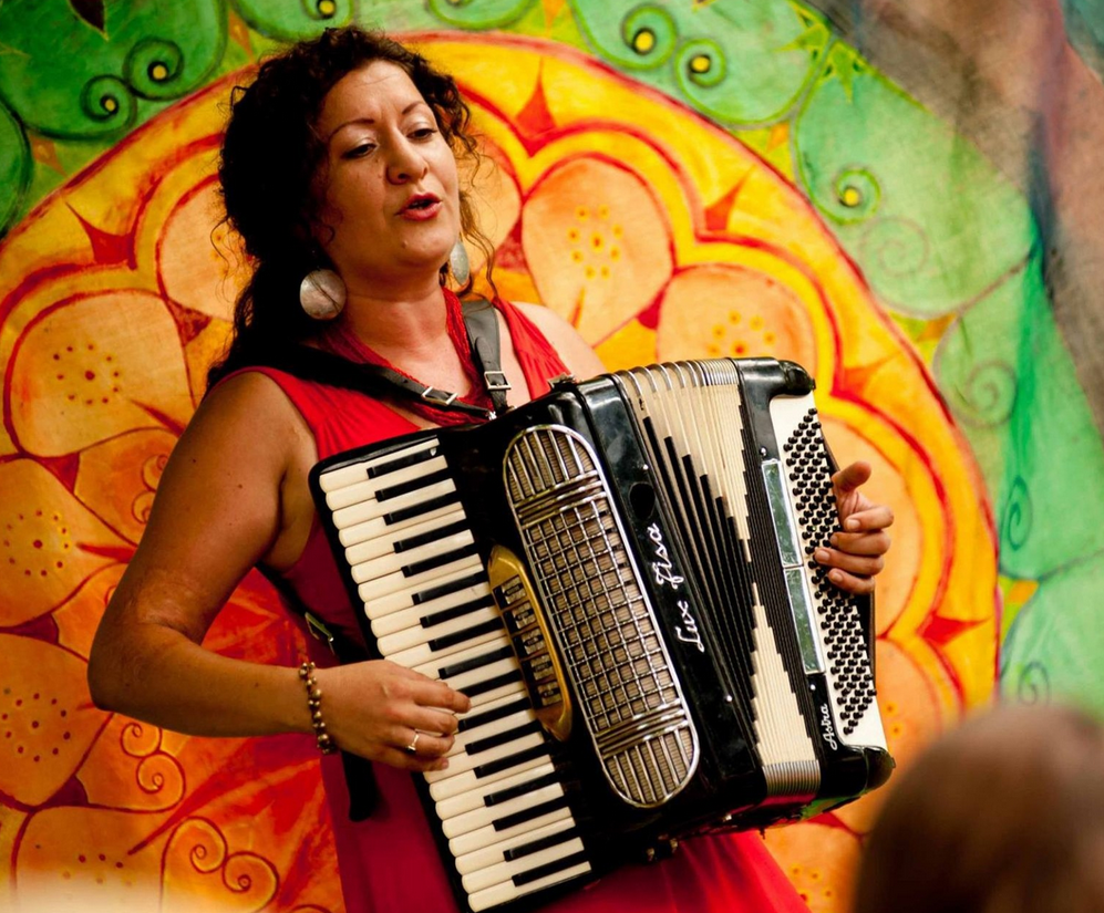 Artystka z akordeonem na kolorowym tle.