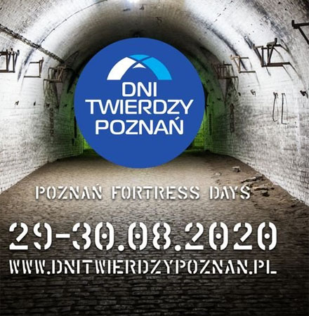 Fort od srodka. Ściany i sklepienie z cegeł. Na środku logo imprezy: białe litery na niebieskim tle.