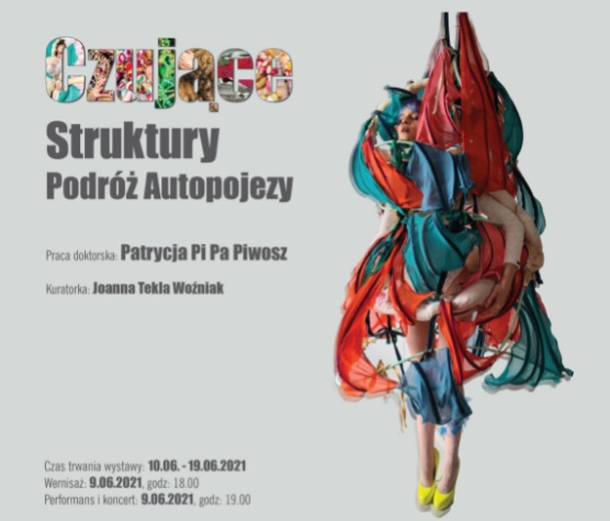 Po lewej tytuł wystawy. Po prawej kobieta ubrana w strój zrobiony z kawałków materiału jaby na stelażach.