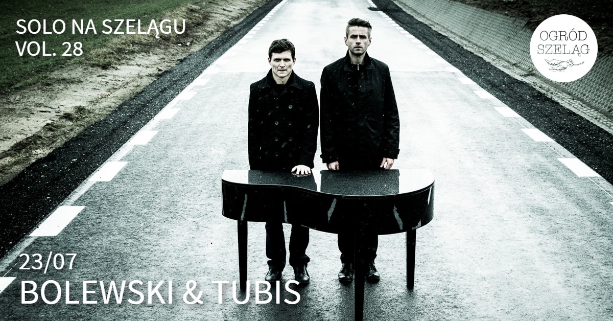 Dwóch mężczyzn ubranych na czarno, stoją na ulicy za małym fortepianem.