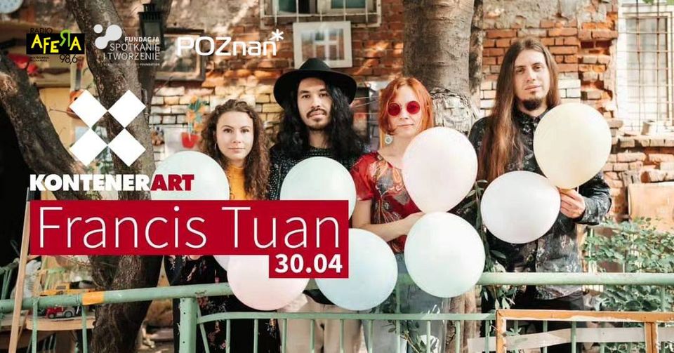 Czworo ludzi trzymający balony w rękach pozują na tle podówrka kamienicy.