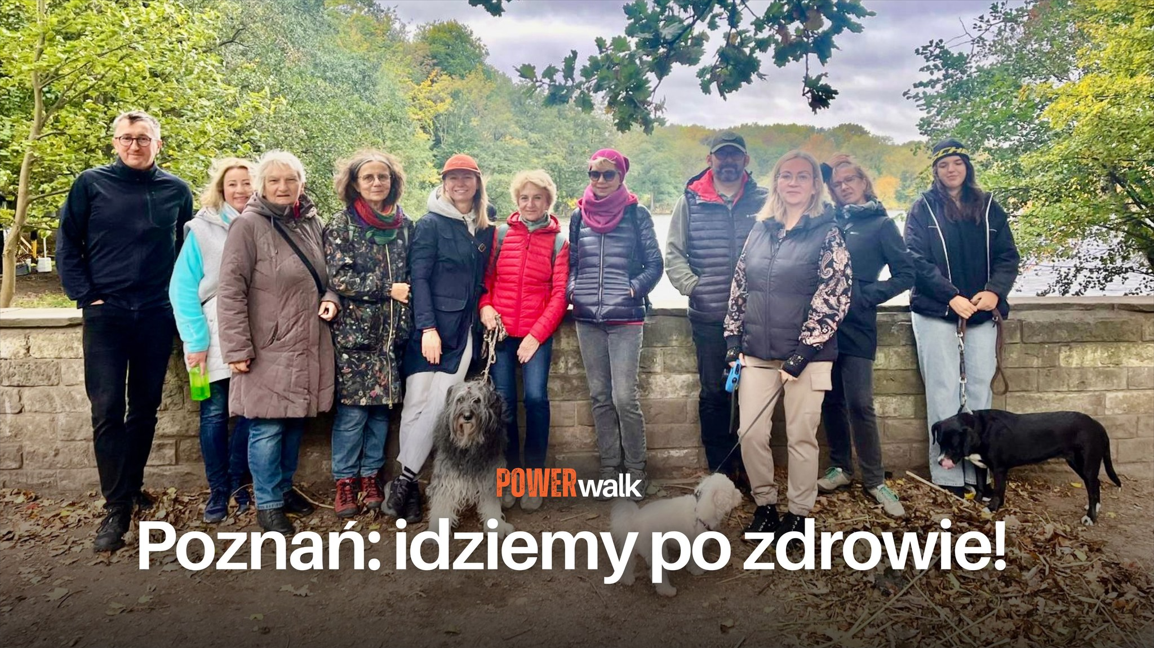 Grupa ludzi pozująca do zdjęcia z kilkoma psami. W tle drzewa oraz jezioro. Na froncie tytuł wydarzenia "Power walk" i hasło: "Poznań: idziemy po zdrowie!"