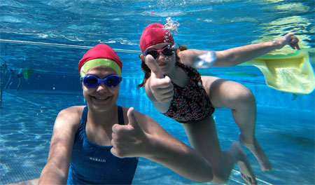 Dziewczynki z kciukiem uniesionym w górę, w basenie.