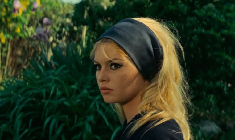 Zdjęcie, tawarz Brigitte Bardot na tle roślin.