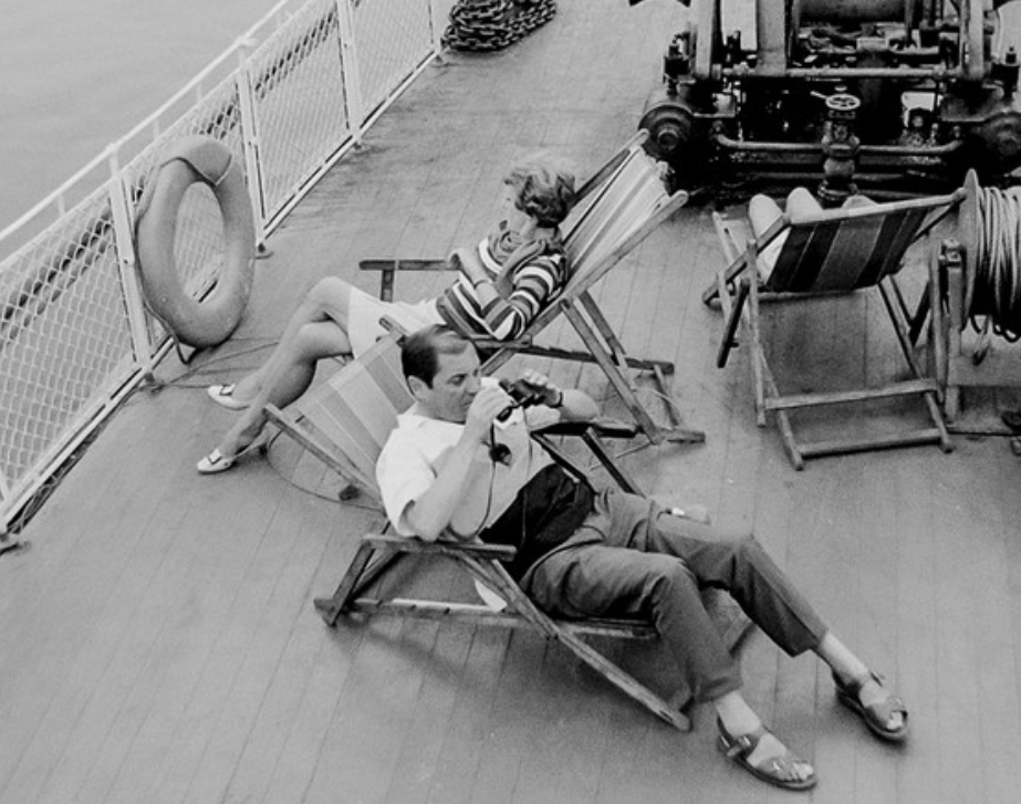 Kadr przedstawia dwie osoby, kobietę i mężczyznę, leżących na leżaczkach na pokładzie statku wycieczkowego. Patrzymy na nich z lotu ptaka.