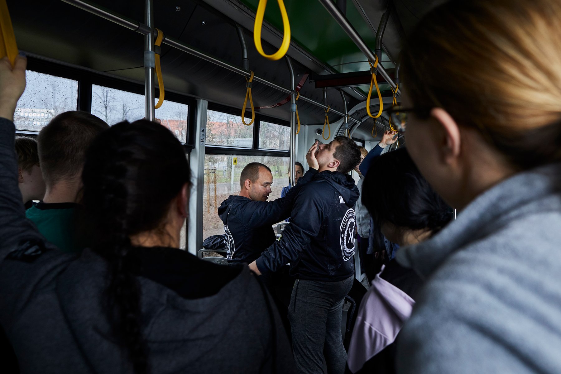 Dwóch mężczyzn prezentuje jak samoobronić się w tramwaju. pokazowi przyglądają się uczestnicy.