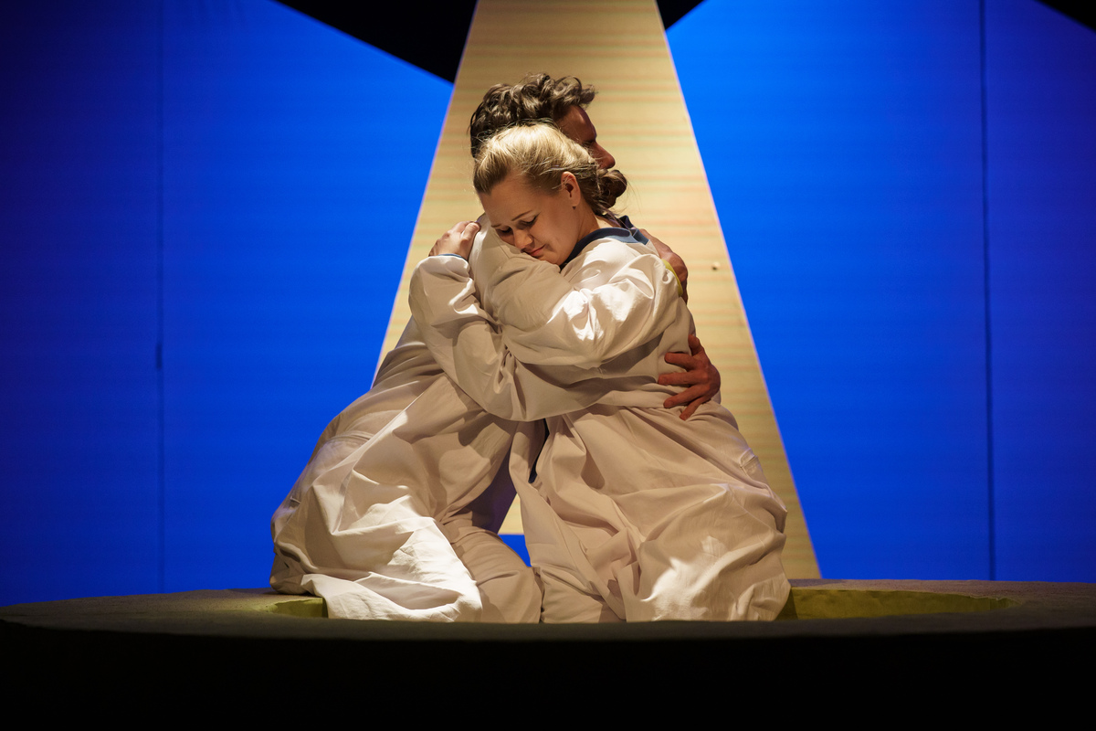 Zdjęcie ze spektaklu - kobieta i mężczyzna siedząc przytulają się do siebie.