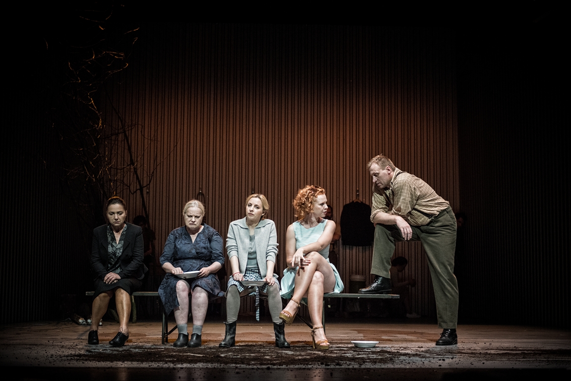 Zdjęcie z przedstawienia - cztery kobiety siedzące na ławce, na skraju ławki mężczyzna, który stoi i jedną nogą opiera się o ławkę.