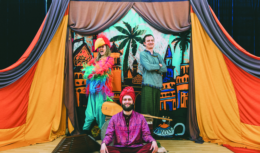 Osoby w orientalnych strojach na scenie teatralnej.