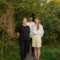 Troje młodych ludzi stoi na ścieżce w zielonym ogrodzie.