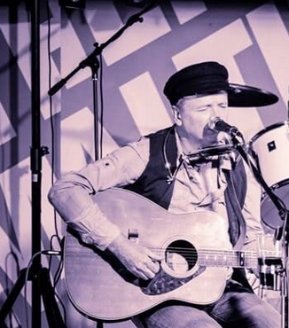 Biało-czarne zdjęcie artysty na scenie.