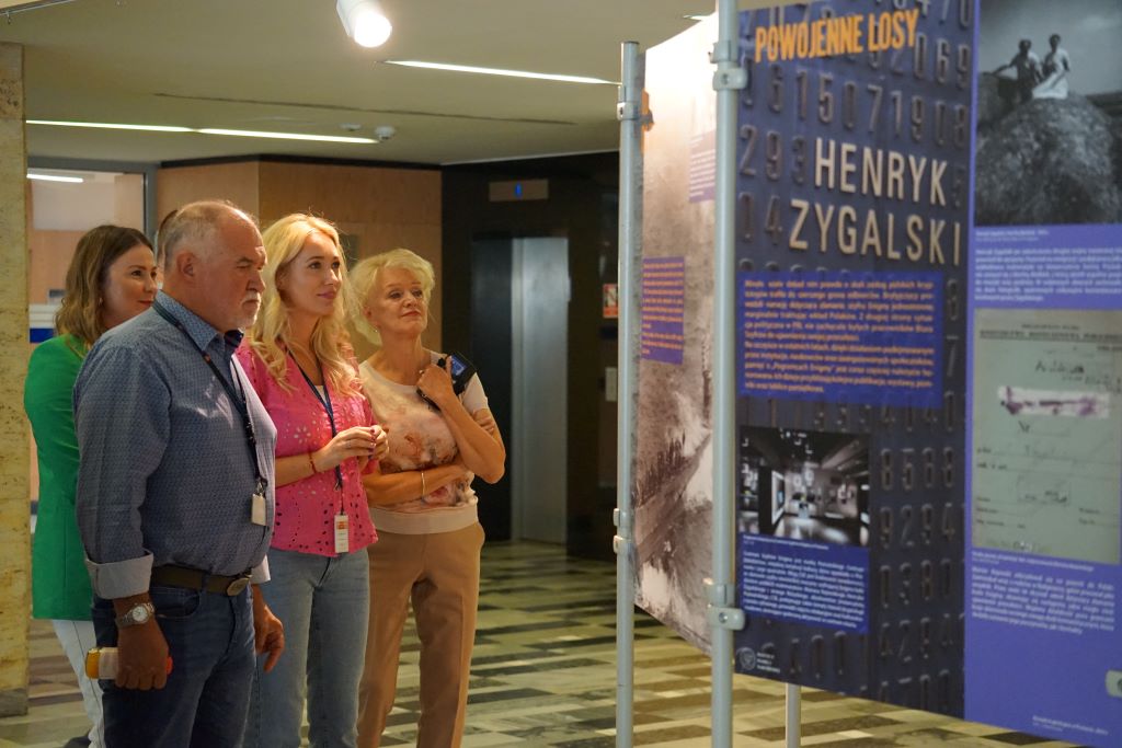 Zdjęcie, grupa osób ogląda wystawę w holu Urzędu Wojewódzkiego w Poznaniu.