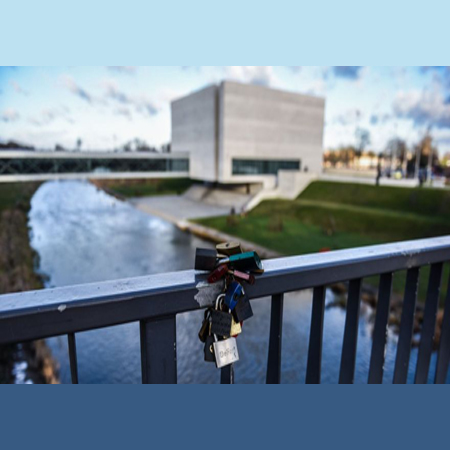 Widok na Wartę i Bramę Poznania: na pierwszym planie poręcz mostu z przypiętymi kłódkami