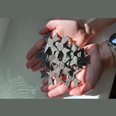 Dłonie trzymające nazistowskie odznaczenia - fragment wykopalisk