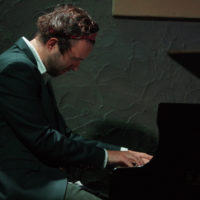 Zdjęcie artysty przy fortepianie.