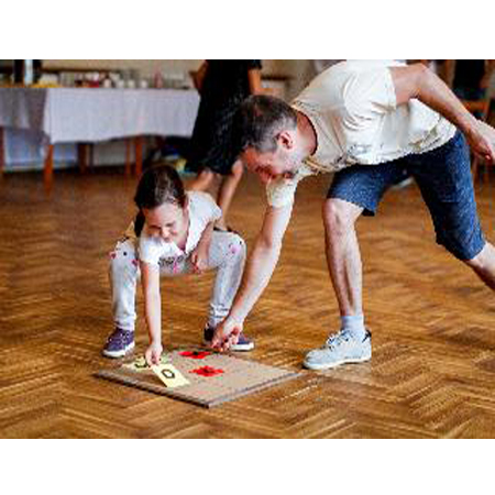 Dziewczynka z ojcem grają w grę planszową leżącą na podłodze.