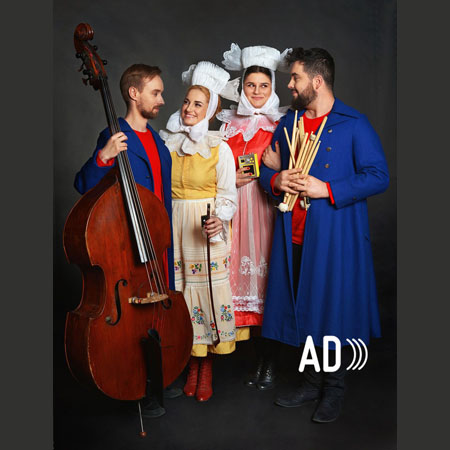 Na fotografii widać członków i członkinie zespołu Dagadana. Mężczyźni mają ubrane niebieskie, długie płaszcze i czerwone koszule pod nimi, kobiety zaś biało-żółte i biało-czerwone stroje stylizowane na ludowe. Muzyk po lewej stronie trzyma kontrabas. Artystki i artyści stoją obok siebie i spoglądają na siebie uśmiechnięci.