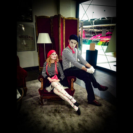 Fotografia ze spektaklu "Lekcja Pantomimy" Teatru HoM, Tychy. Na pierwszym planie mim Pierrot i aktorka dramatyczna Zosia. Aktorzy siedzą na fotelu, patrząc w kierunku fotografa.