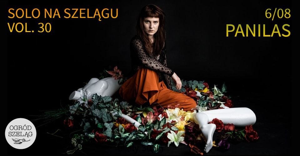 Na zdjęciu postać siedzącej artystki na czarnym tle.