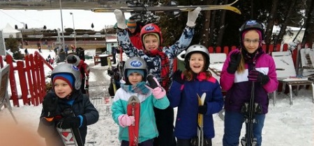 Grupa dzieci w zimowych kurtkach na dworze.