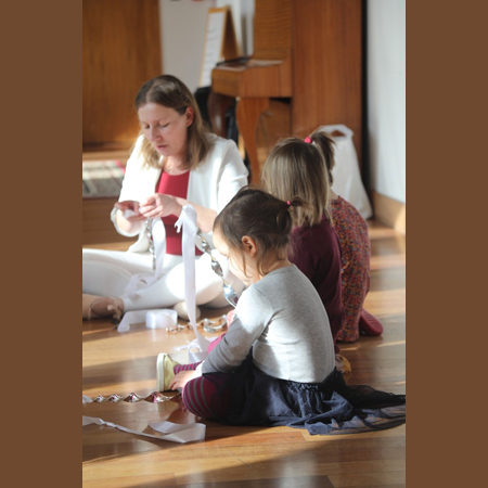 Zdjęcie przedstawia grupę małych dzieci na warsztatach wraz z prowadzącą.