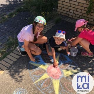 uismiechnięte dzieci przy rysunku wykonanym kredą na ziemi