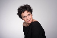 Zdjęcie Danieli Popławskiej w czarnej bluzce na jasno-szarym tle.